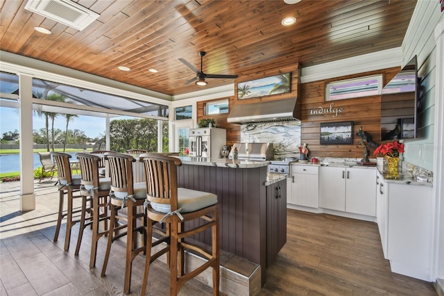 kitchen with wooden walls, white cabinets, wooden ceiling, and dark hardwood / wood-style floors