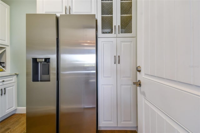 kitchen featuring white cabinets, stainless steel refrigerator with ice dispenser, and light wood-type flooring