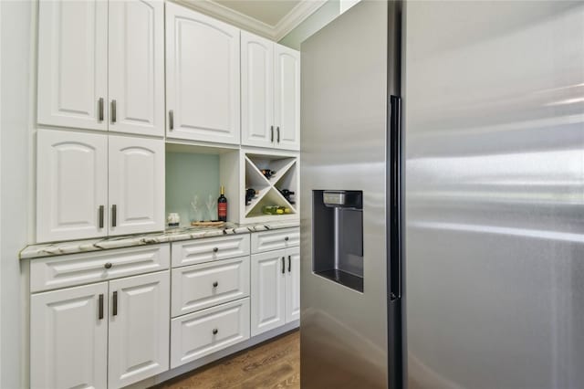 bar with light stone counters, dark hardwood / wood-style floors, stainless steel fridge, white cabinets, and ornamental molding