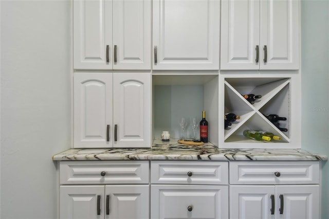 bar with white cabinets and light stone counters