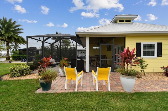 rear view of property featuring a patio, glass enclosure, and a lawn