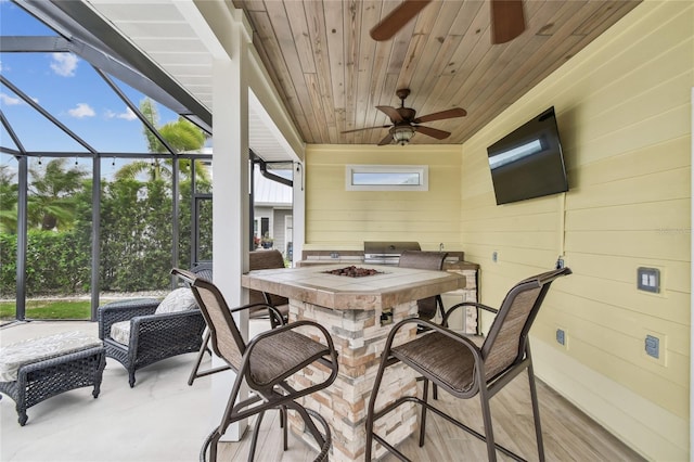 sunroom / solarium with ceiling fan, plenty of natural light, and wooden ceiling