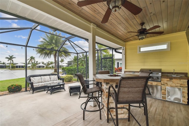 view of patio / terrace with glass enclosure, an outdoor kitchen, a water view, sink, and a grill