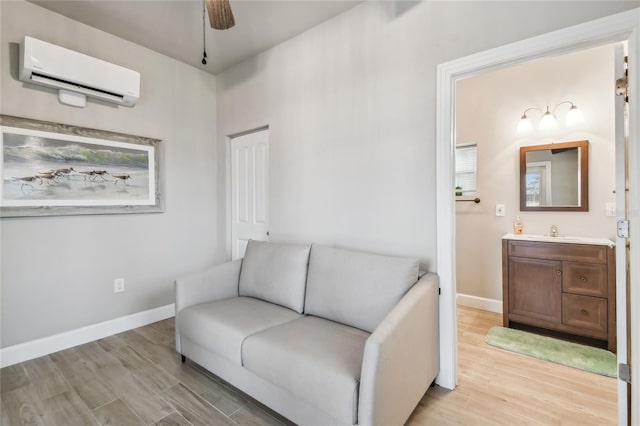 living area with light hardwood / wood-style floors, an AC wall unit, ceiling fan, and sink