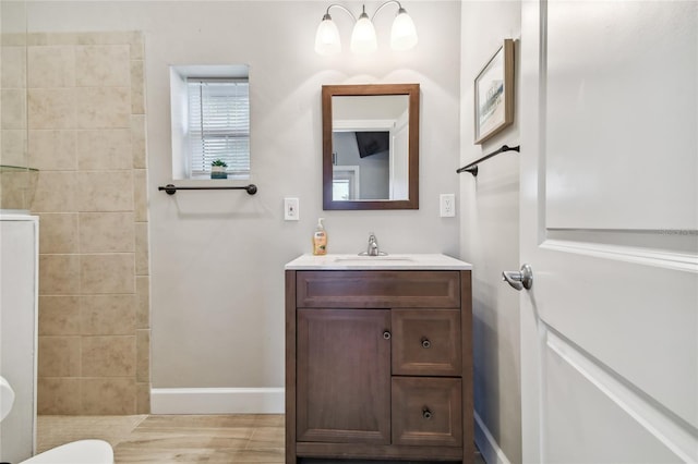 bathroom with hardwood / wood-style floors, vanity, and a tile shower