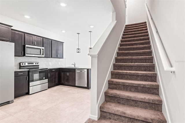 kitchen with sink, hanging light fixtures, stainless steel appliances, backsplash, and dark brown cabinets