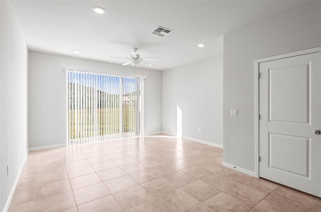 spare room featuring a textured ceiling, ceiling fan, and light tile patterned flooring