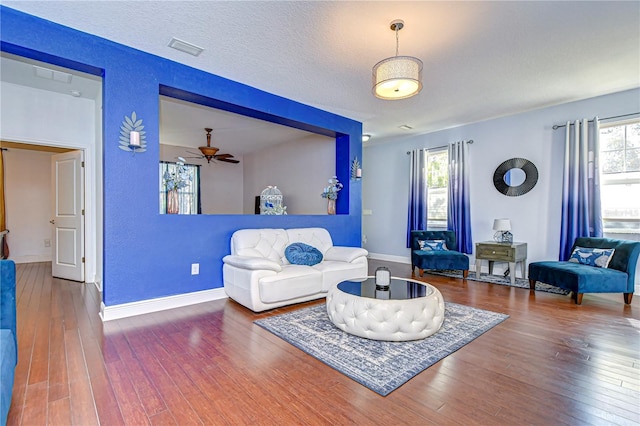 living room with a textured ceiling, hardwood / wood-style flooring, and ceiling fan