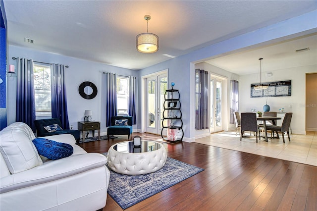 living room with a wealth of natural light, french doors, and wood-type flooring