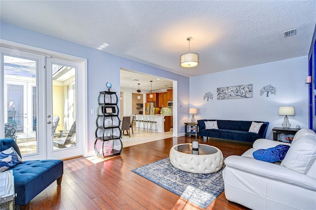 living room featuring french doors, a textured ceiling, and hardwood / wood-style flooring