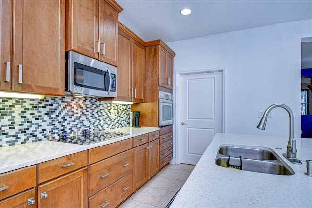 kitchen featuring sink, decorative backsplash, light tile patterned floors, appliances with stainless steel finishes, and light stone counters