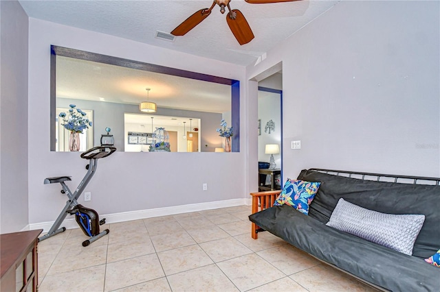 living room featuring tile patterned flooring, ceiling fan, and a textured ceiling