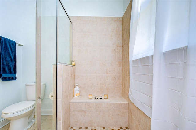 bathroom featuring tile patterned floors, toilet, and a tile shower