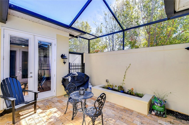 view of patio featuring glass enclosure, grilling area, and french doors