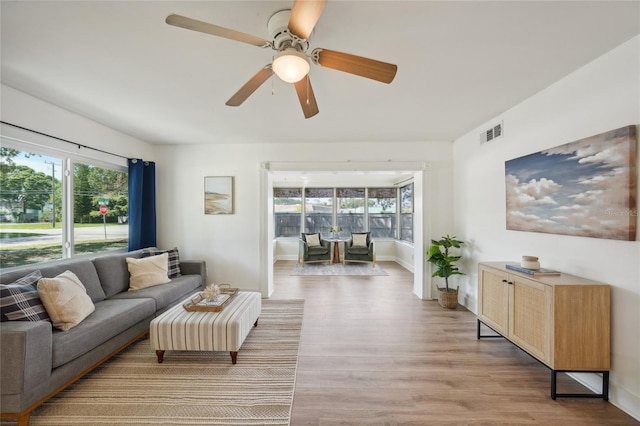 living room featuring a wealth of natural light, light wood-type flooring, and ceiling fan