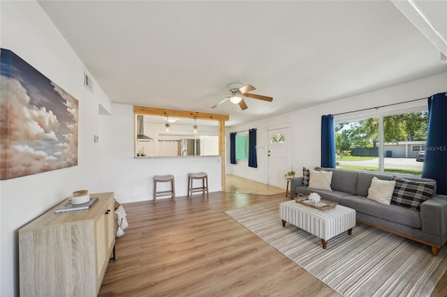 living room with wood-type flooring, ceiling fan, and beam ceiling