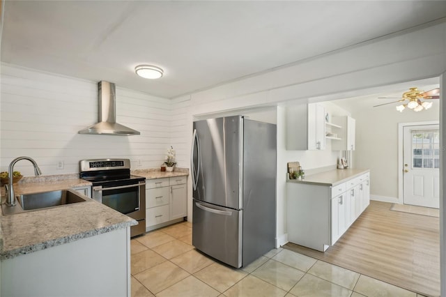 kitchen featuring sink, stainless steel appliances, white cabinetry, and wall chimney range hood