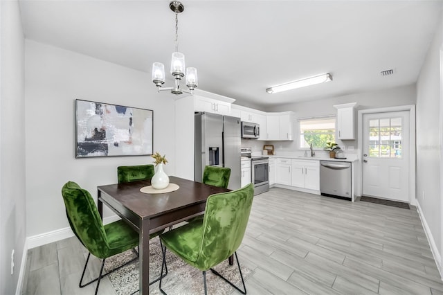 dining area featuring a notable chandelier, sink, and light hardwood / wood-style flooring