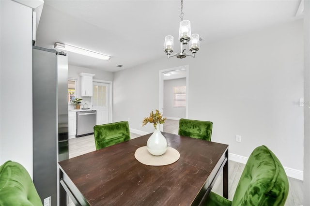 dining area with light hardwood / wood-style flooring and a notable chandelier