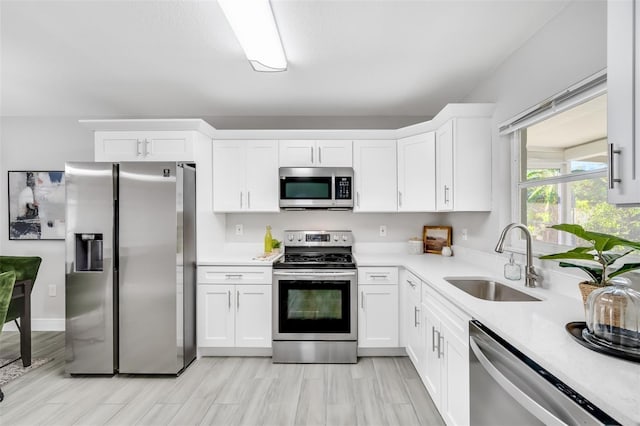 kitchen featuring sink, white cabinets, stainless steel appliances, and light hardwood / wood-style floors