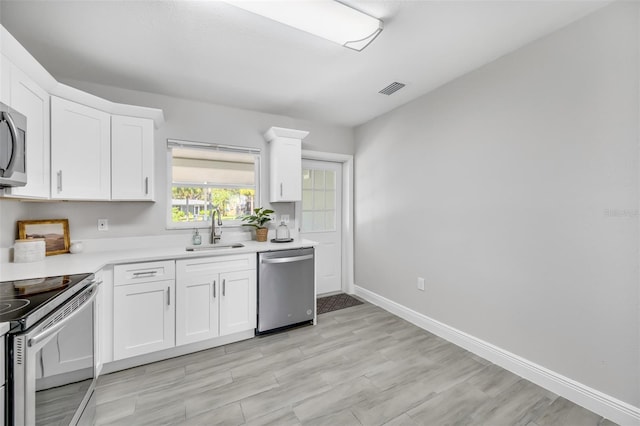 kitchen featuring stainless steel dishwasher, sink, light hardwood / wood-style flooring, white electric stove, and white cabinetry