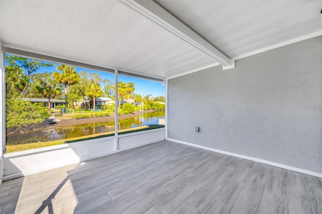 unfurnished sunroom with beam ceiling and a water view