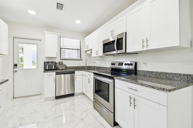 kitchen featuring white cabinetry, appliances with stainless steel finishes, and dark stone countertops