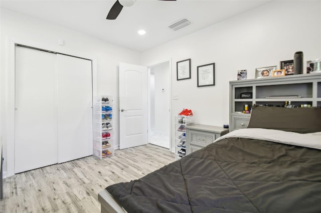 bedroom with light wood-type flooring, ceiling fan, and a closet