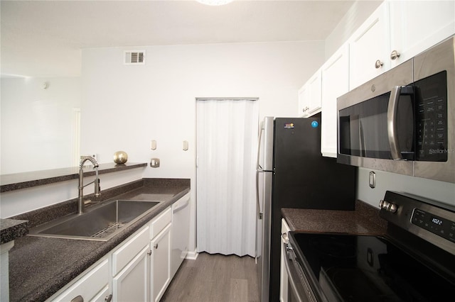 kitchen featuring stainless steel appliances, a sink, visible vents, white cabinetry, and dark countertops