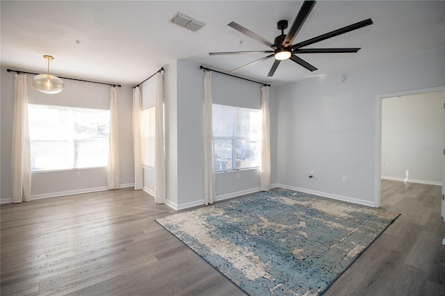 unfurnished room with baseboards, visible vents, ceiling fan, and wood finished floors