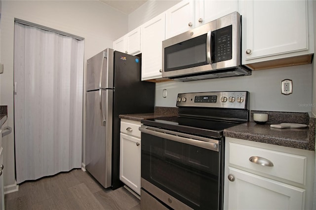 kitchen with stainless steel appliances, dark wood-style flooring, dark countertops, and white cabinetry