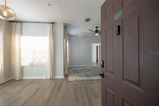 corridor featuring light wood-style flooring, visible vents, and baseboards