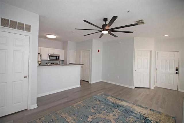 unfurnished living room with dark wood-style floors, ceiling fan, visible vents, and baseboards