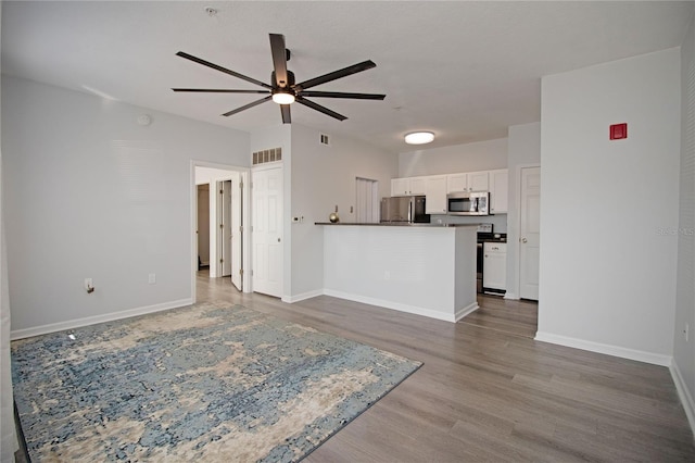 unfurnished living room with baseboards, visible vents, and wood finished floors