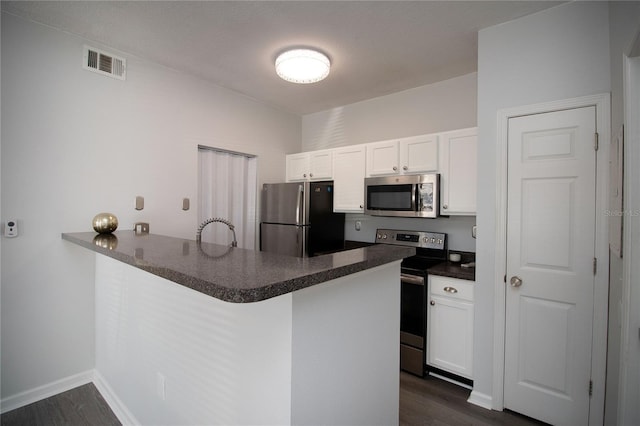 kitchen with stainless steel appliances, dark countertops, visible vents, white cabinets, and a peninsula