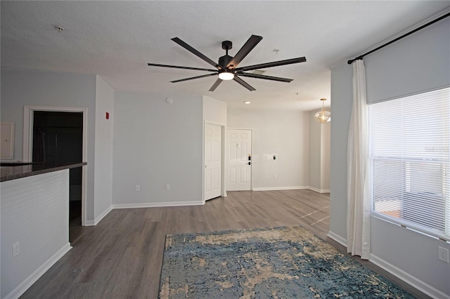 spare room featuring a textured ceiling, baseboards, and wood finished floors