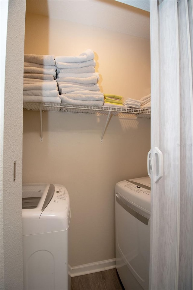 washroom featuring laundry area, baseboards, dark wood-style flooring, and independent washer and dryer