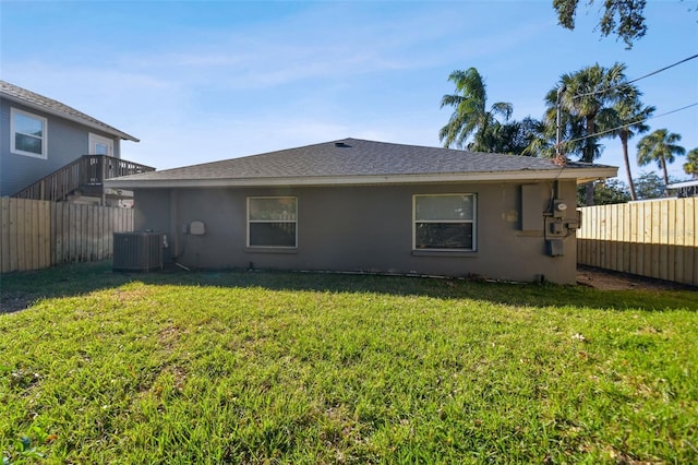 rear view of property with a lawn and cooling unit