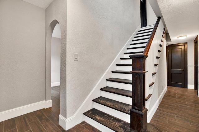 stairs featuring wood-type flooring and a textured ceiling