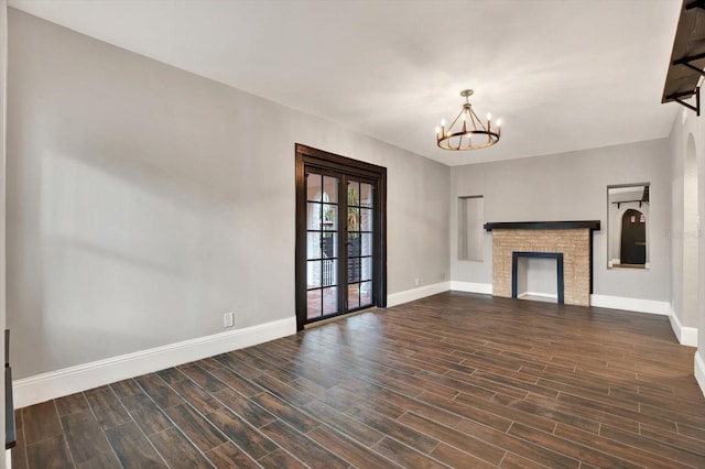 unfurnished living room with a chandelier, french doors, dark hardwood / wood-style flooring, and a fireplace