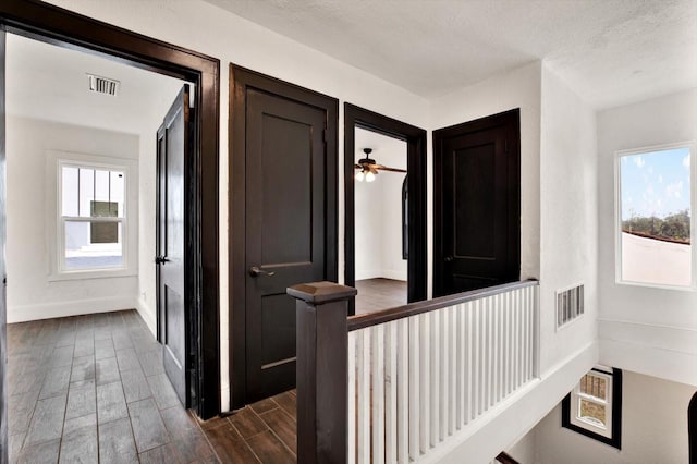 corridor featuring a textured ceiling and dark hardwood / wood-style floors