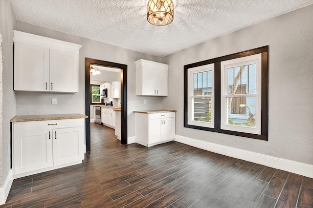 kitchen with dark hardwood / wood-style flooring, white cabinets, stainless steel appliances, and a textured ceiling