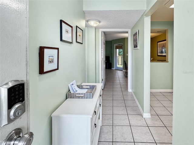 hall with light tile patterned floors and a textured ceiling