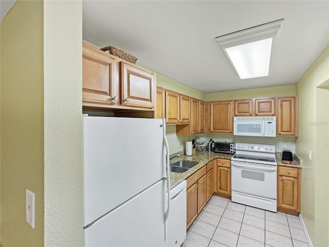 kitchen with light stone counters, sink, light tile patterned flooring, and white appliances