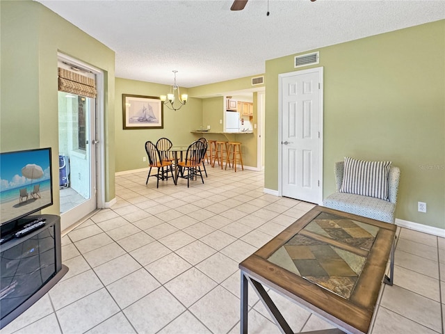 living room featuring ceiling fan with notable chandelier, light tile patterned floors, and a textured ceiling