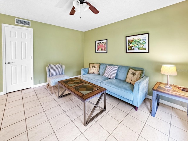 living room featuring ceiling fan, light tile patterned flooring, and a textured ceiling