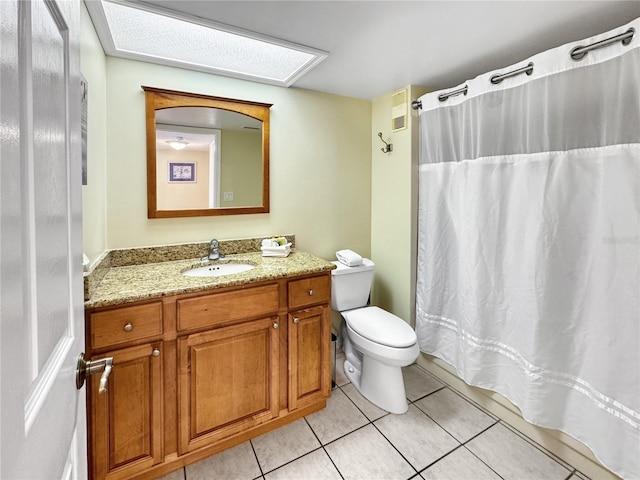 bathroom featuring tile patterned flooring, vanity, toilet, and a skylight