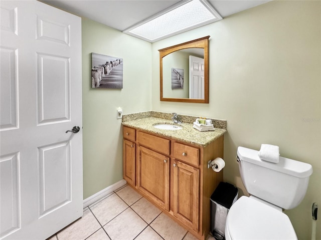 bathroom featuring tile patterned flooring, vanity, a skylight, and toilet