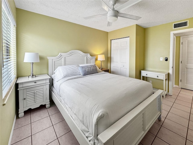 bedroom with ceiling fan, a closet, light tile patterned floors, and multiple windows