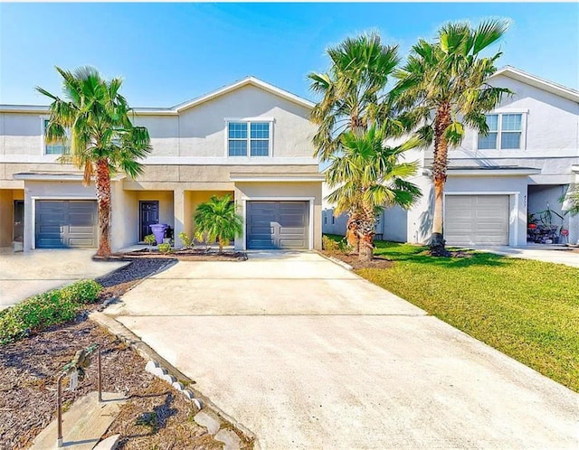 view of front of house featuring driveway, a front lawn, an attached garage, and stucco siding